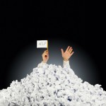 hands and sign sticking out of pile of paper