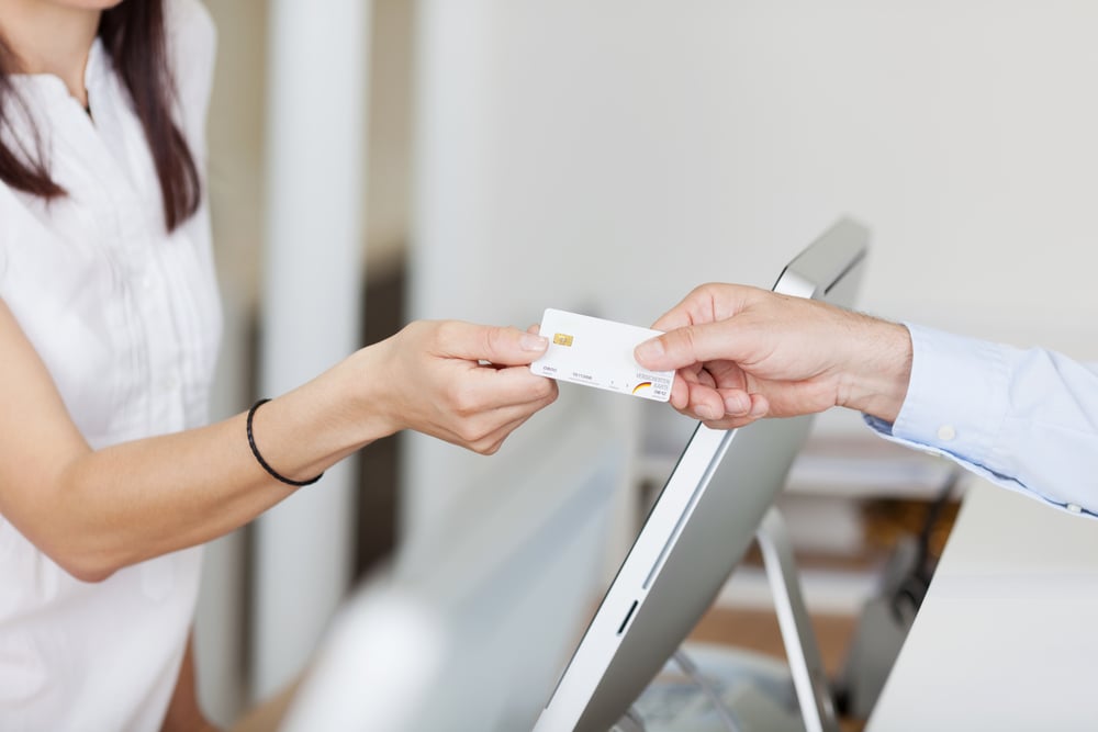 Closeup of receptionist receiving card from male patient in dentist clinic