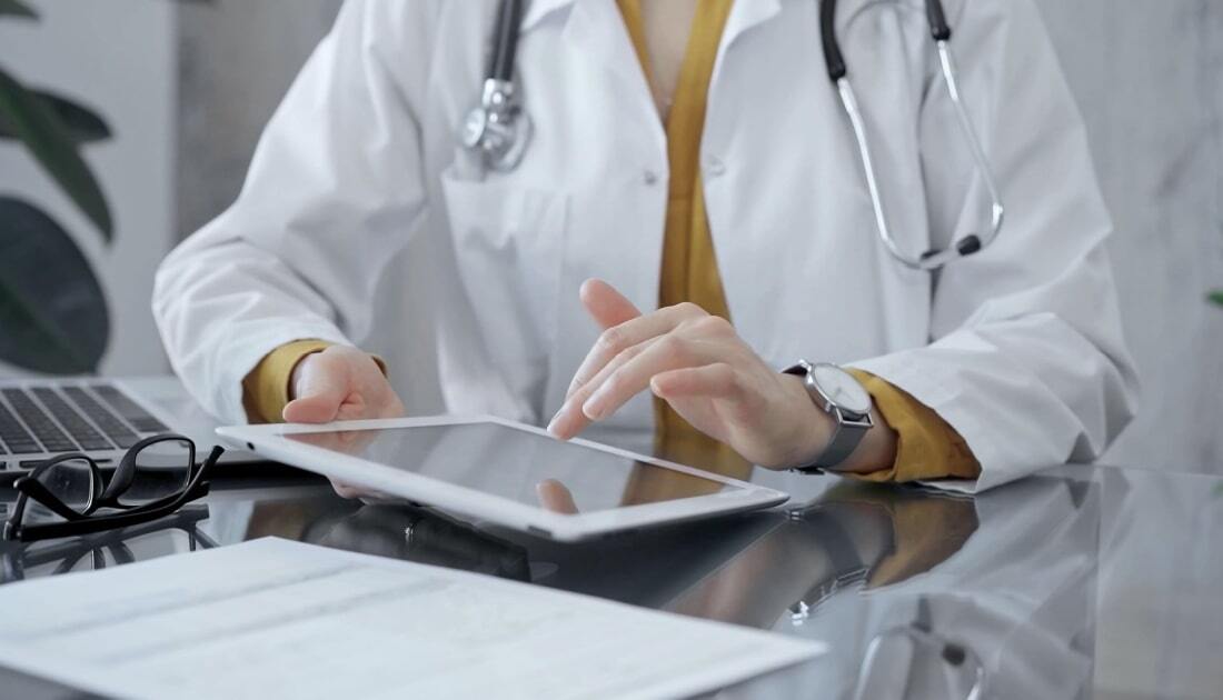 Doctor using a tablet at a desk, illustrating what EMR systems are in healthcare.