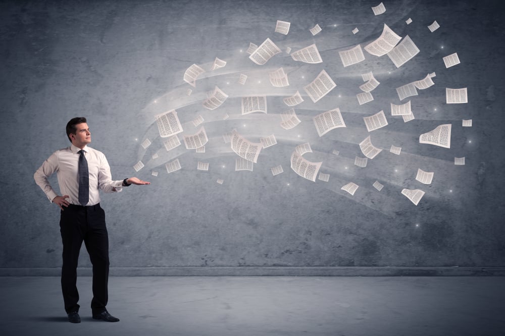 Caucasian businessman holding newspapers, which are floating away from his hands