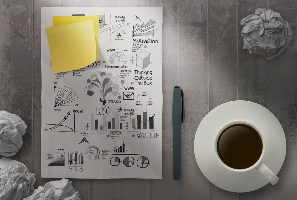 coffee cup with crumpled paper of hand drawn business strategy and blank sticky note background as concept